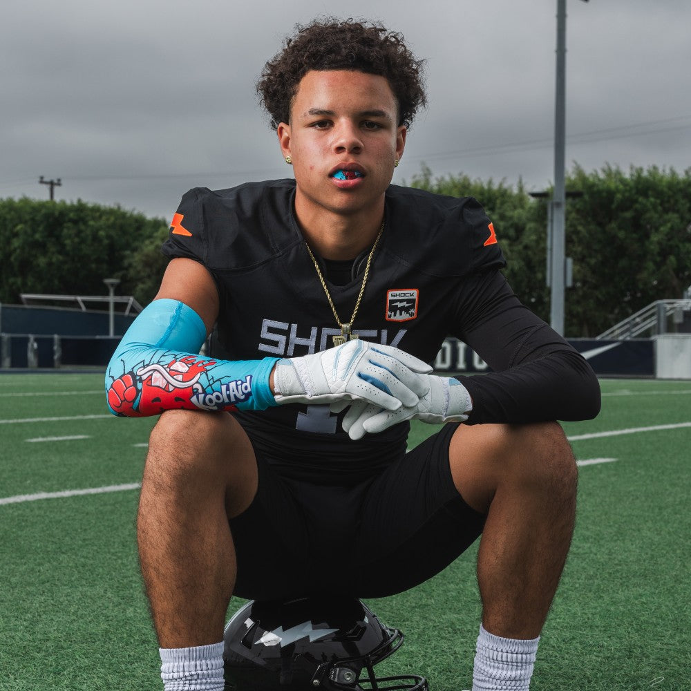 Youth Tackle Football Athlete Wearing  Showtime Kool-Aid Tropical Punch Compression Arm Sleeve and Tropical Punch Flavor Gel Max Lip Guard
