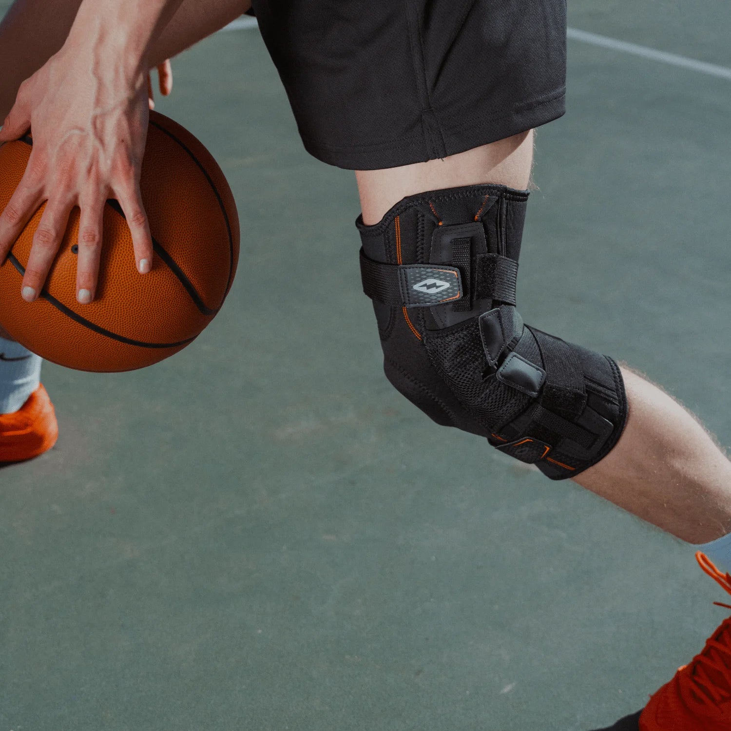 Person holding a basketball with a knee brace on a court