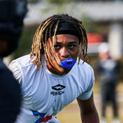 Football player in white uniform wearing a blue Shock Doctor Max AirFlow Lip Guard during game action.