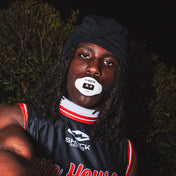 Football player in black and red uniform wearing a white Shock Doctor Max AirFlow Lip Guard at night.