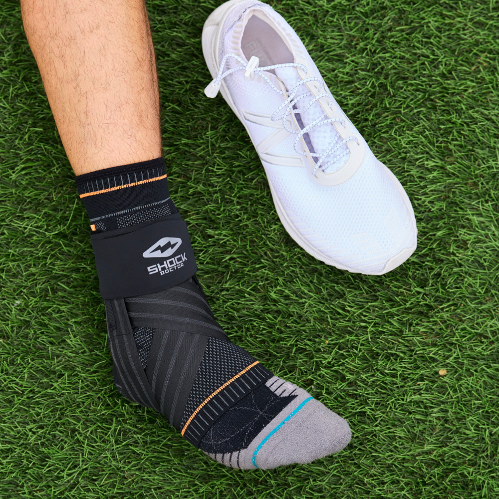 Shock Doctor Ultra Knit Ankle Brace with Figure 6 Strap & Stays - On Model - Side View of Ankle Brace on Grass Field