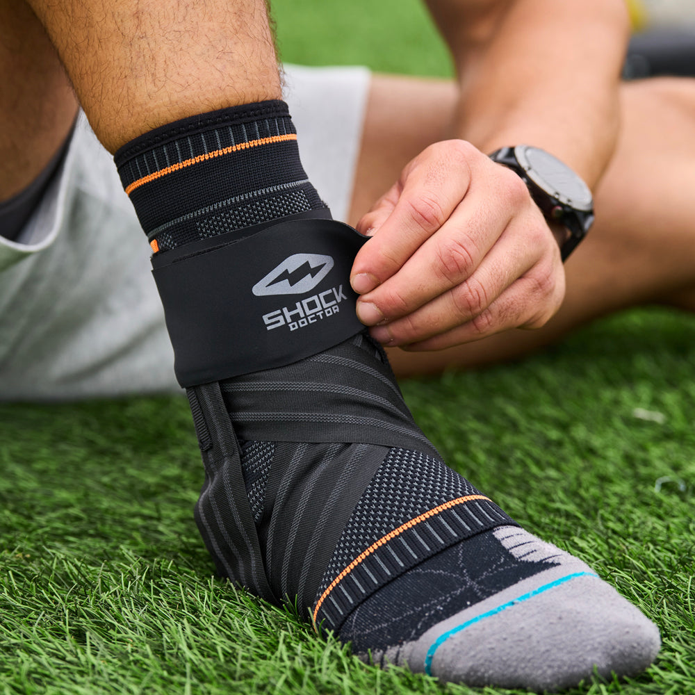 Athlete Strapping on Shock Doctor Ultra Knit Ankle Brace with Figure 6 Strap & Stays