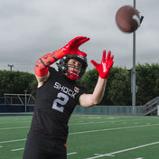 Youth Tackle Football Athlete Catching Football While Wearing Shock Doctor Showtime Kool-Aid Cherry Red Compression Arm Sleeve and Kool-Aid Cherry Flavor Gel Max Power Mouthguard with Kool-Aid Cherry Flavor Chin Guard