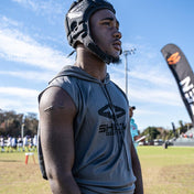 Youth Football Player Wearing Performance Grey Sleeveless Athletic Hoodie by Shock Doctor, designed for sports and training. Features soft, flexible fabric for comfort and fast drying.