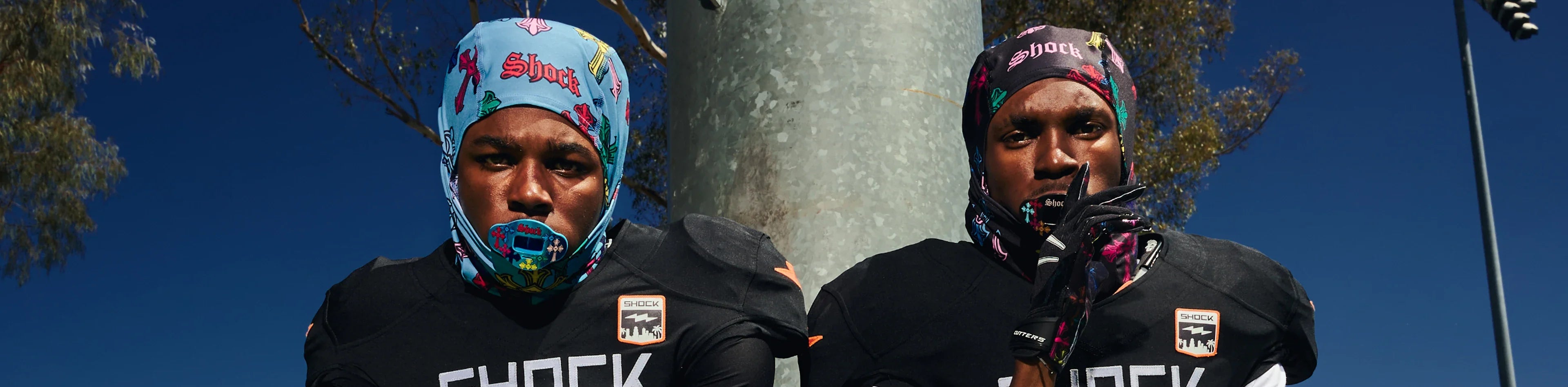 Two football players wearing colorful Shock patterned skull caps under their helmets
