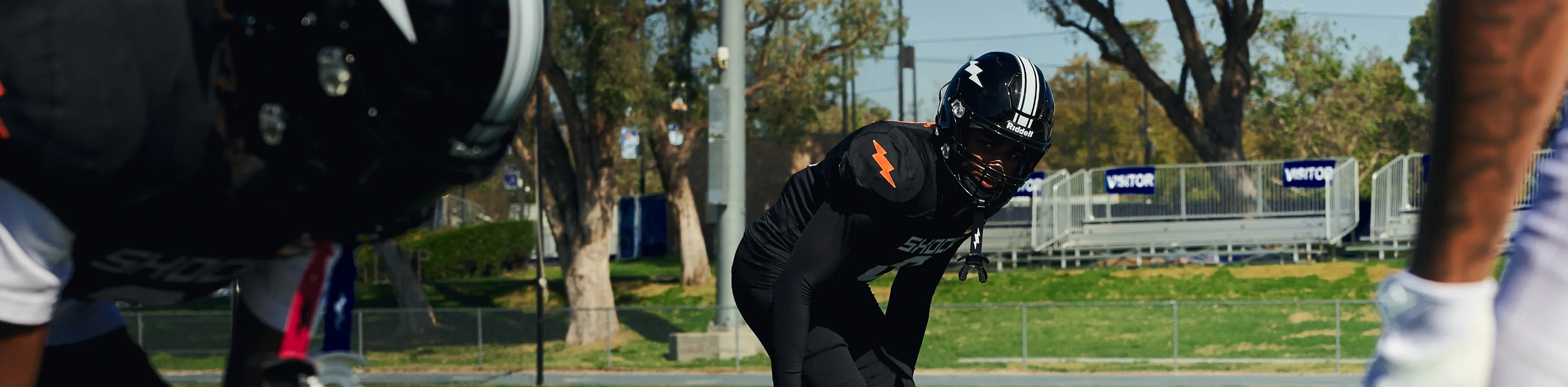 Football player in black Shock Doctor compression gear and helmet in a three-point stance