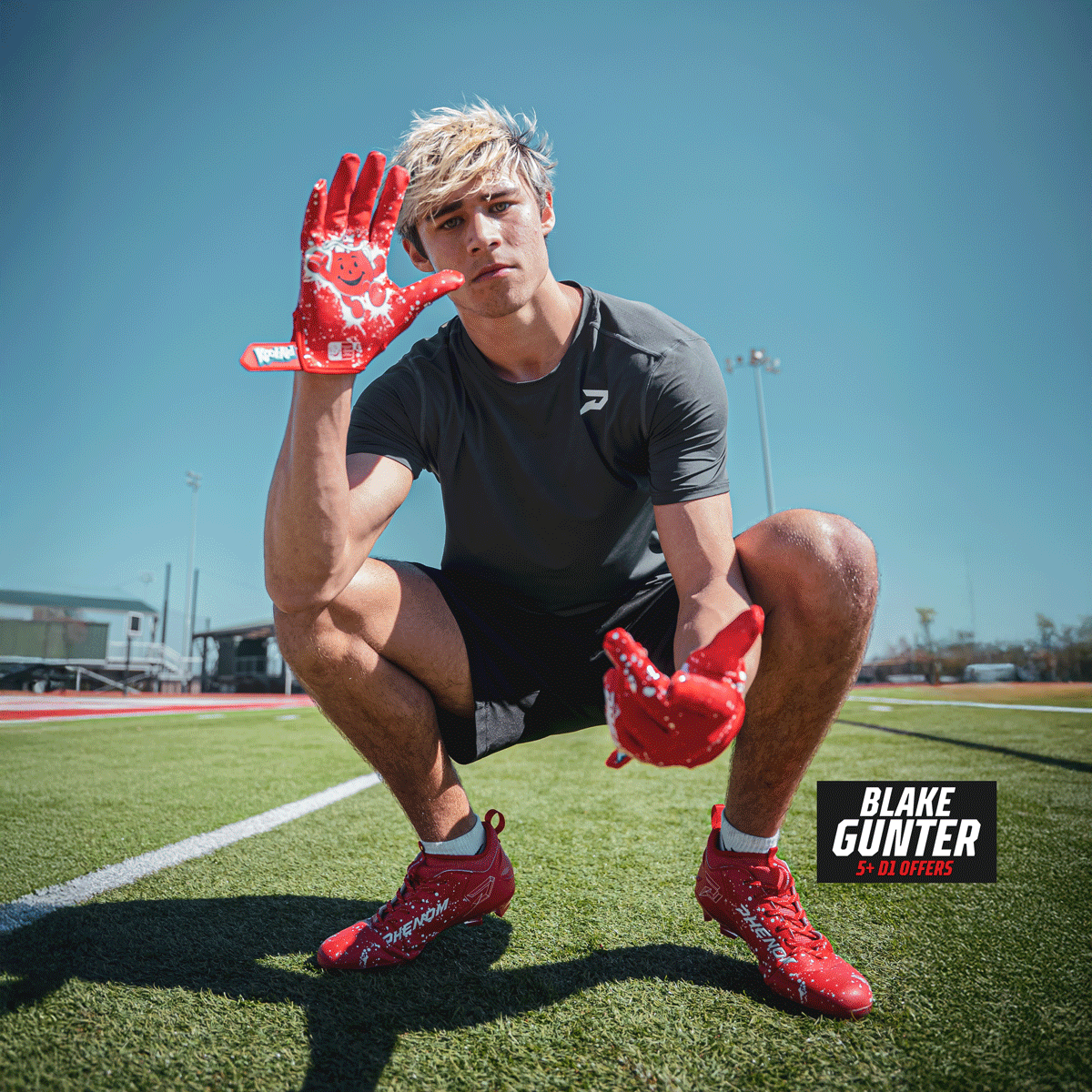 Recruit Blake Gunter crouching on turf in Kool-Aid Cherry cleats by Phenom Elite, holding up a Kool-Aid Man glove