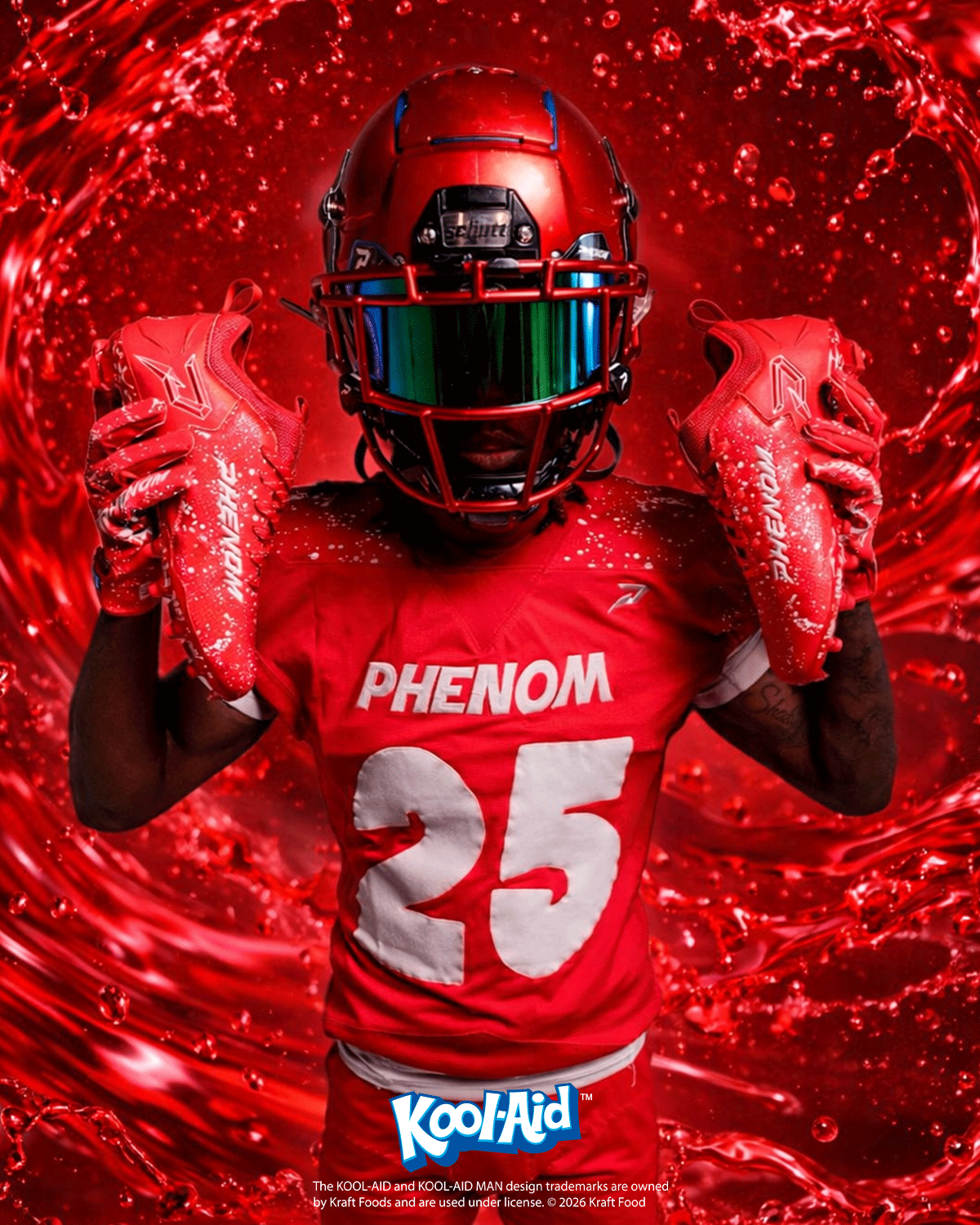 Football player in a red Phenom uniform holding up Kool-Aid Cherry cleats against a red liquid splash