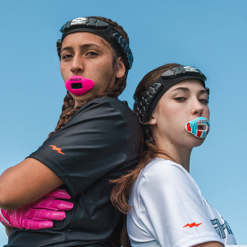 Two Youth Flag Football Athletes Wearing a Shock Doctor Pink Max AirFlow Lip Guard and an ICEE Max AirFlow Lip Guard (both are wearing a Shock Doctor Protective HEX® Headband