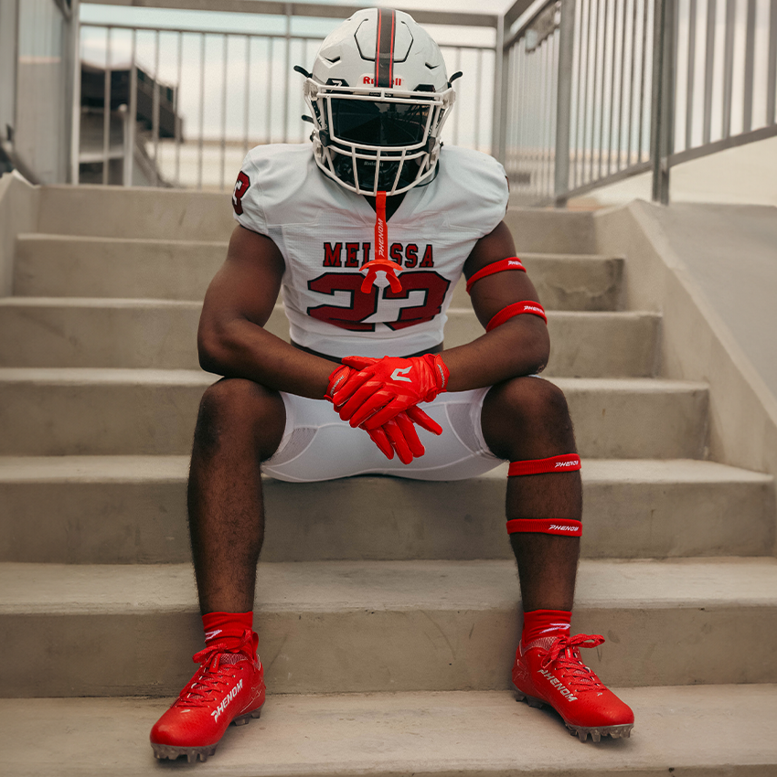 Person in football uniform sitting on steps wearing red and white gear