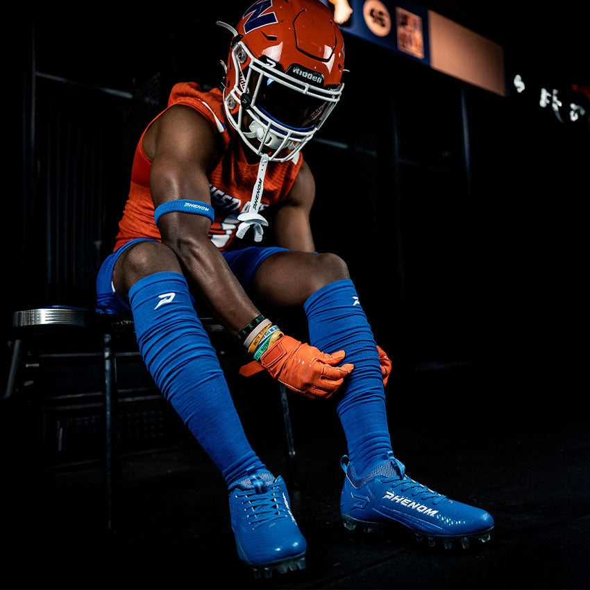 Football player in orange and blue uniform sitting on a bench.