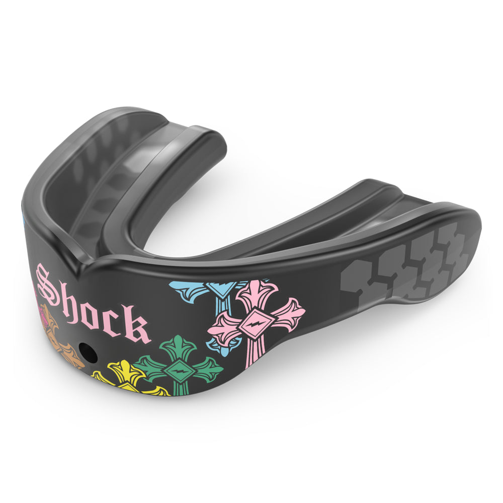 Shock Doctor Gel Max Power Print mouthguard in Divine Drip, shown at a three-quarter angle. Black mouthguard with multicolored gothic cross graphics in pink, blue, green, and yellow, "Shock" lettering in Old English script, and a honeycomb-pattern back channel with a center breathing hole.