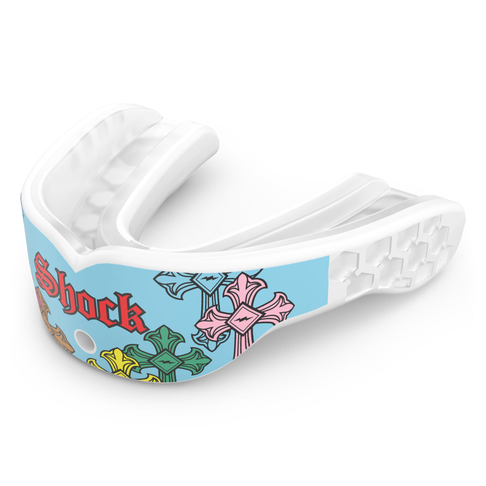 Shock Doctor Gel Max Power Print mouthguard in Blue Divine Drip, shown at a three-quarter angle. Light blue and white mouthguard with multicolored gothic cross graphics in pink, green, yellow, and orange, "Shock" lettering in red Old English script, and a honeycomb-pattern back channel with a center breathing hole.