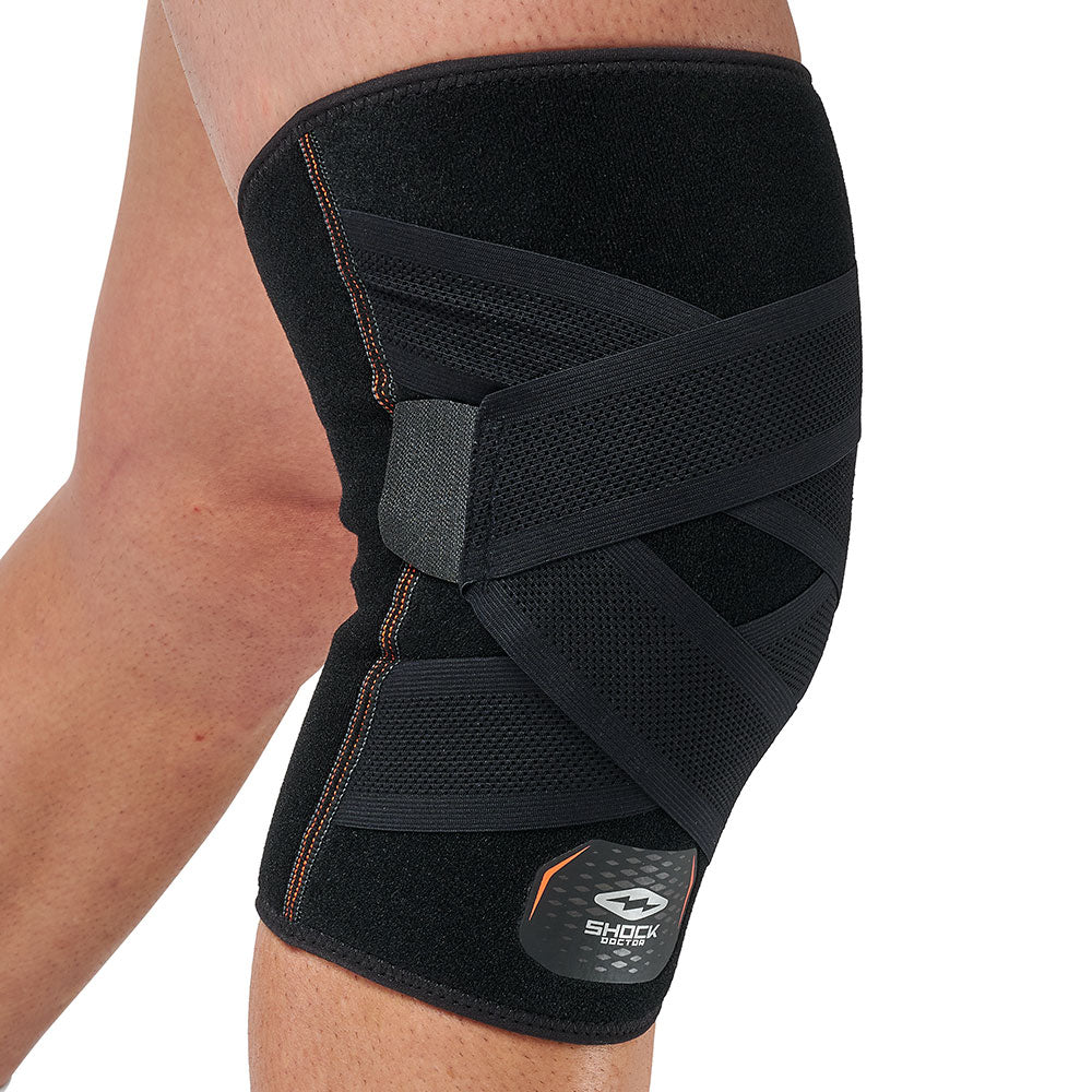 Shock Doctor Cross Compression Knee Sleeve worn on bent knee, three-quarter view highlighting the X-shaped compression strap pattern