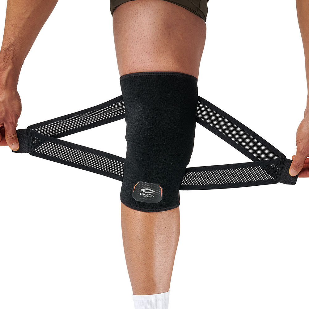 Person putting on Shock Doctor Cross Compression Knee Sleeve, holding open compression straps before wrapping around knee