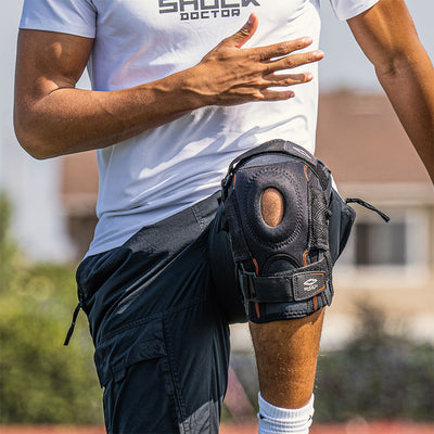 Lifestyle Image of Athlete Wearing Shock Doctor Ultra Knee Support with Bilateral Hinges While Warming Up