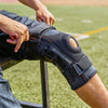 Lifestyle Image of Athlete Sliding On Shock Doctor Ultra Knee Support with Bilateral Hinges
