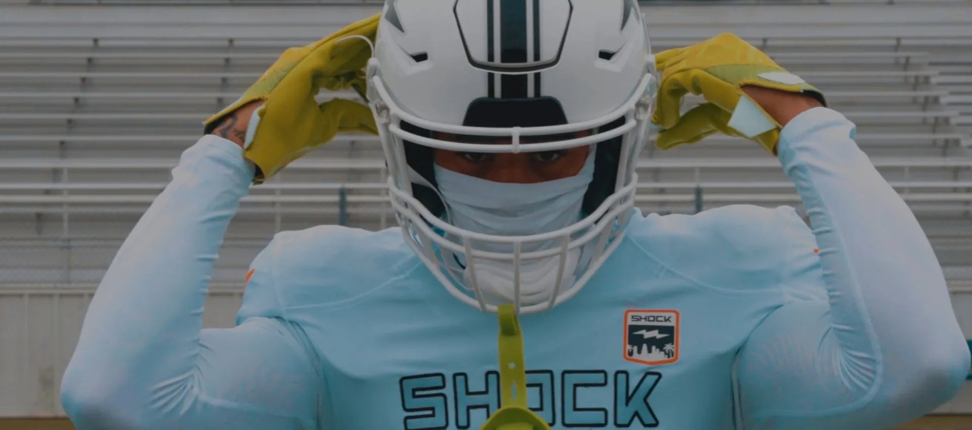 Football Athlete wearing helmet, ski mask, and white jersey with 'Shock' branding.