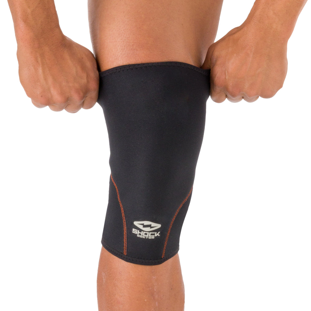 Person pulling on the Shock Doctor Knee Sleeve, showing the stretch fit and easy on/off design