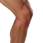 A close-up of a person's leg wearing a thin, bright pink athletic band or waist/hip strap against a plain white background.