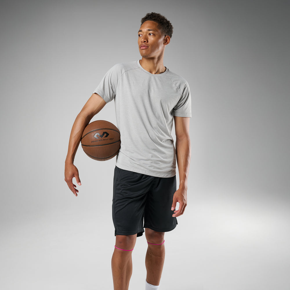 Person holding a basketball against a gray background