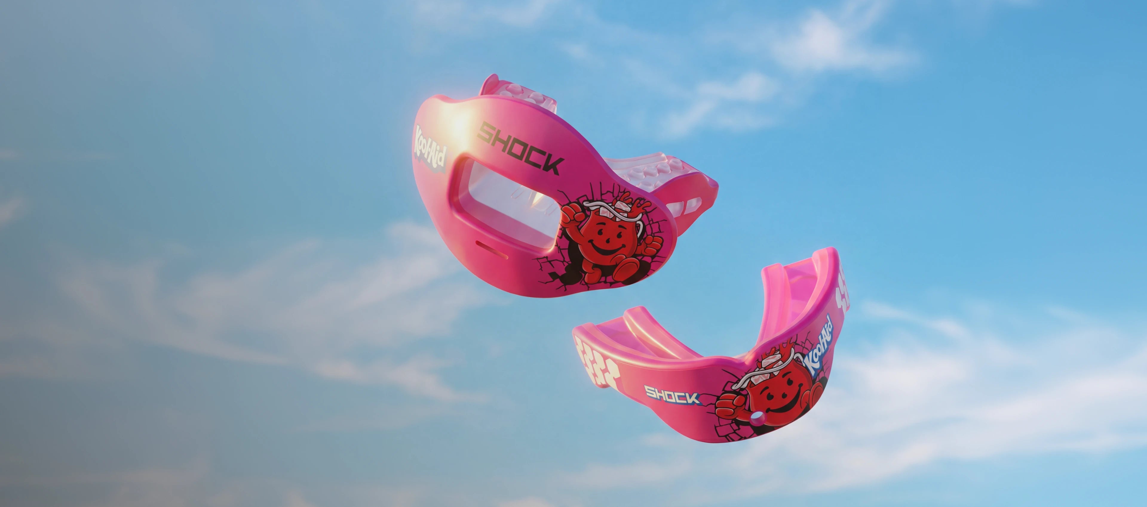Two pink mouthguards with cartoon designs against a blue sky.