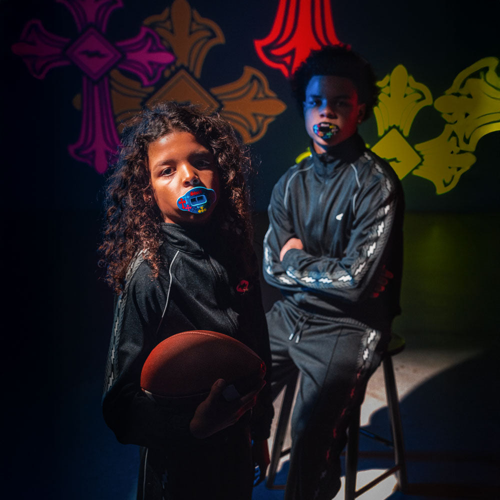 Two youth football athletes wearing football lip guards in dark environment
