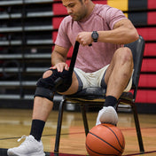 Athlete Strapping on Shock Doctor Knee Brace with Dual Wrap & Heavy-Duty Hinges Before Game