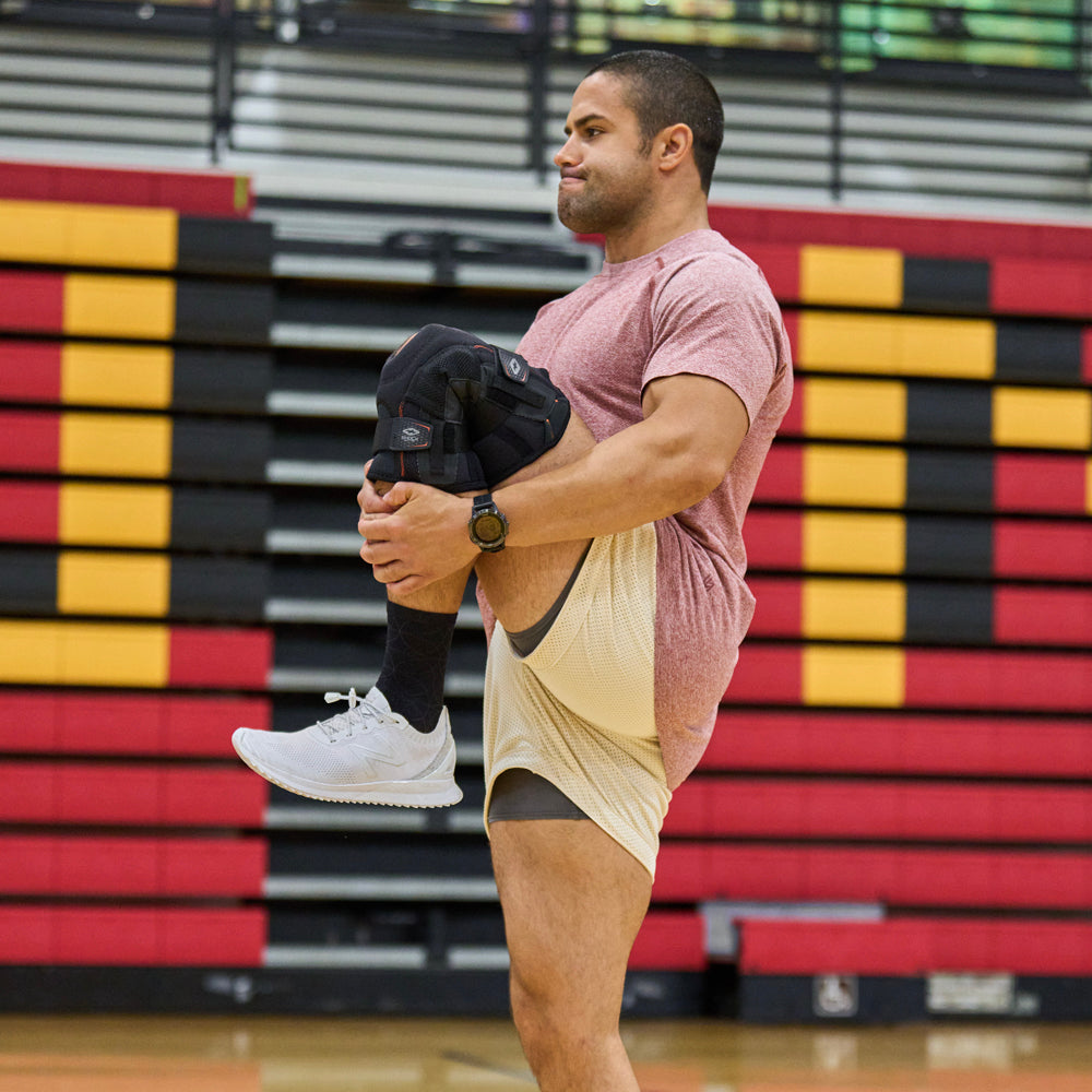 Athlete Stretching Leg Before Practice While Wearing Shock Doctor Ultra Knee Support with Bilateral Hinges 