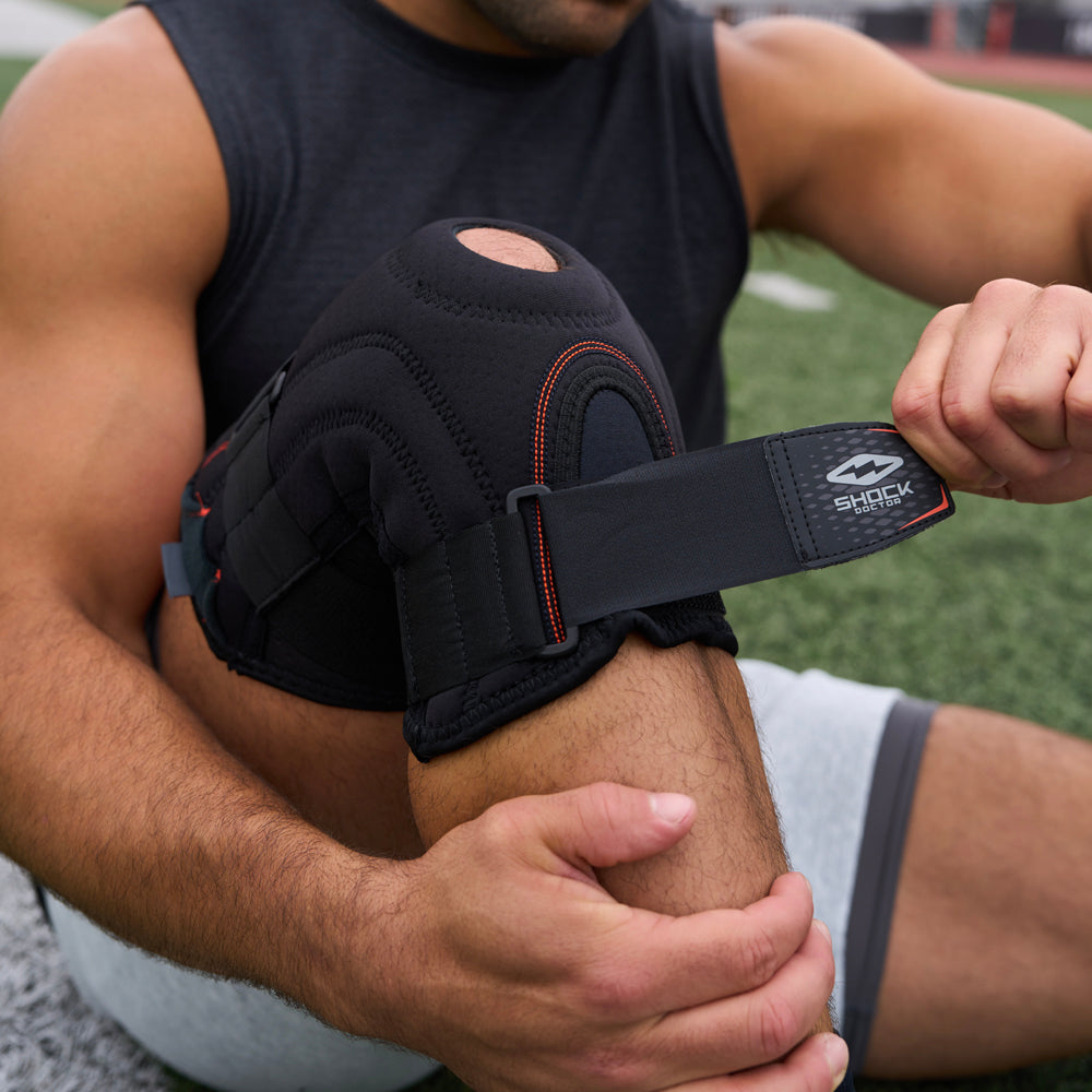 Athlete Adjusting Strap on the Shock Doctor Knee Stabilizer with Flexible Support Stays for a Better Fit